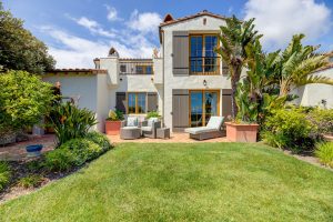 Luxury Mediterranean-style villa at Terranea Resort featuring lush landscaping, sun loungers, and elegant outdoor seating overlooking the ocean under a bright blue sky.