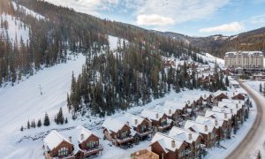 Aerial view of luxury ski chalets at Big Sky Resort surrounded by pine-covered mountains and fresh snow.