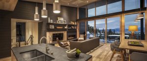 Modern Northstar mountain home with elegant furnishings, floor-to-ceiling windows offering panoramic views of snowy Sierra Nevada mountains and a cable car ascending the slopes.