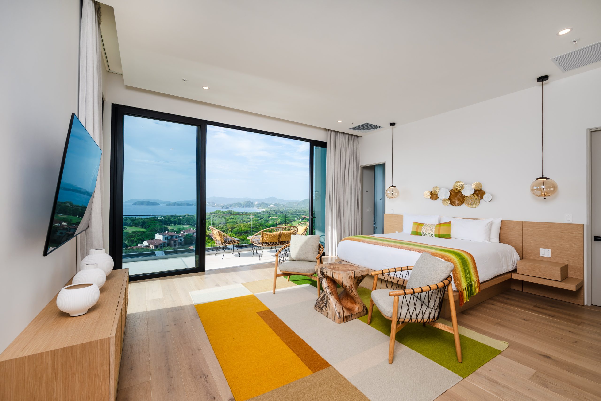 Luxury bedroom with floor-to-ceiling windows overlooking lush greenery and ocean views at the Reserva Conchal penthouse in Costa Rica