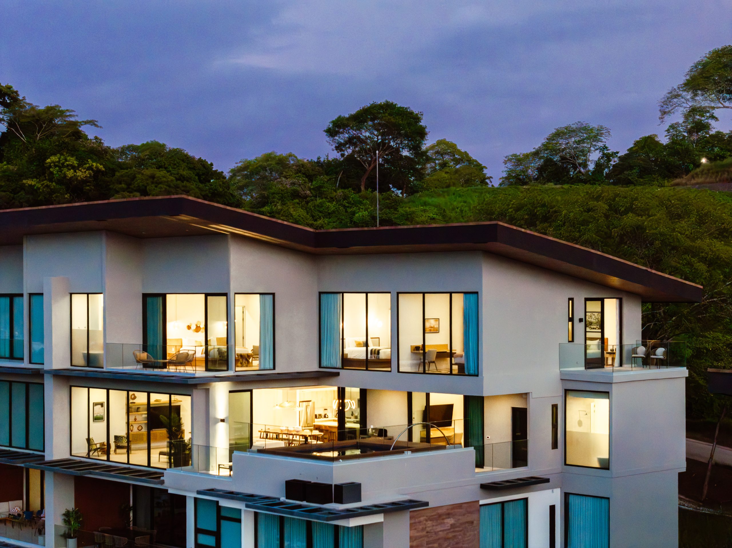 Modern ocean-view penthouse at Reserva Conchal, featuring floor-to-ceiling windows and a private infinity pool overlooking Costa Rica’s lush tropical hillsides at night