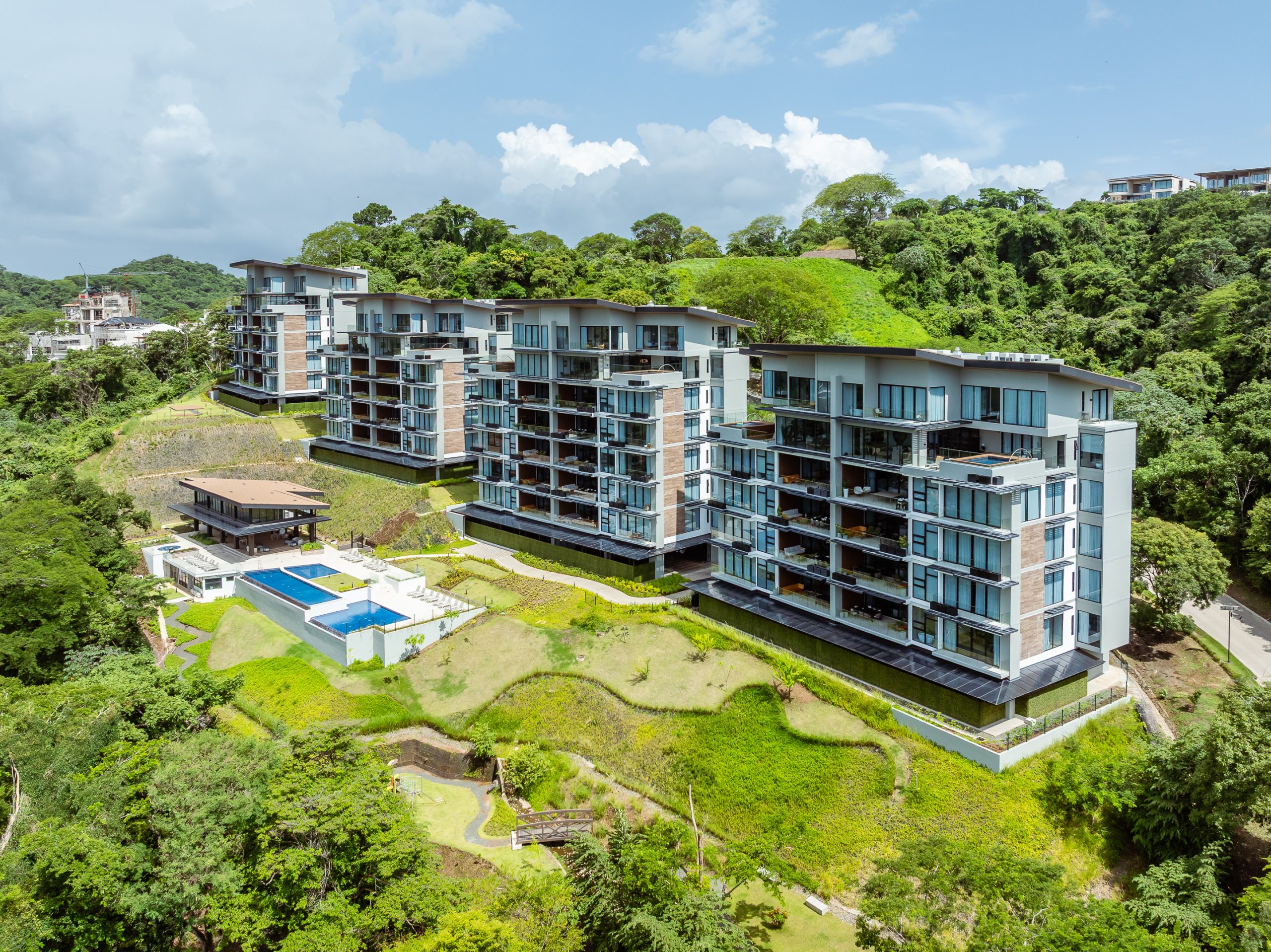 Aerial view of the luxury Solaris residences at Reserva Conchal in Costa Rica, featuring modern ocean-view condominiums surrounded by lush greenery, with a large infinity pool, clubhouse, and landscaped gardens.