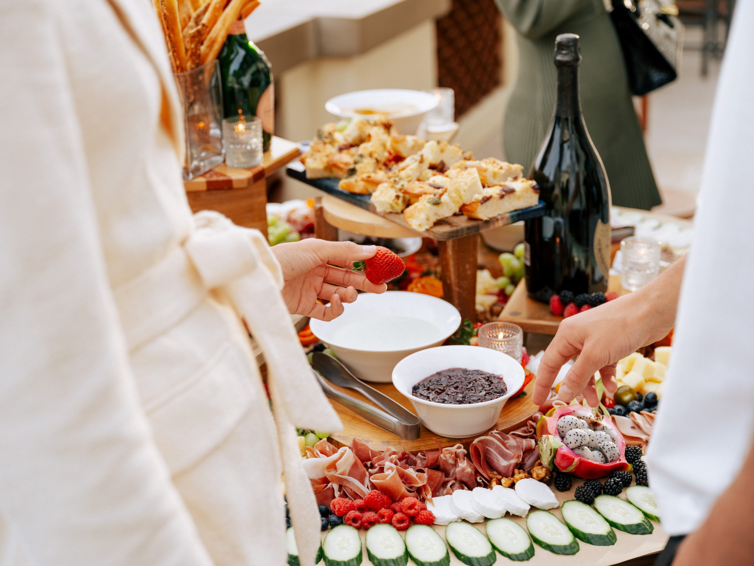 Luxury charcuterie spread at Terranea Resort featuring gourmet cheeses, cured meats, fresh fruit, and champagne, creating an elegant outdoor dining experience.
