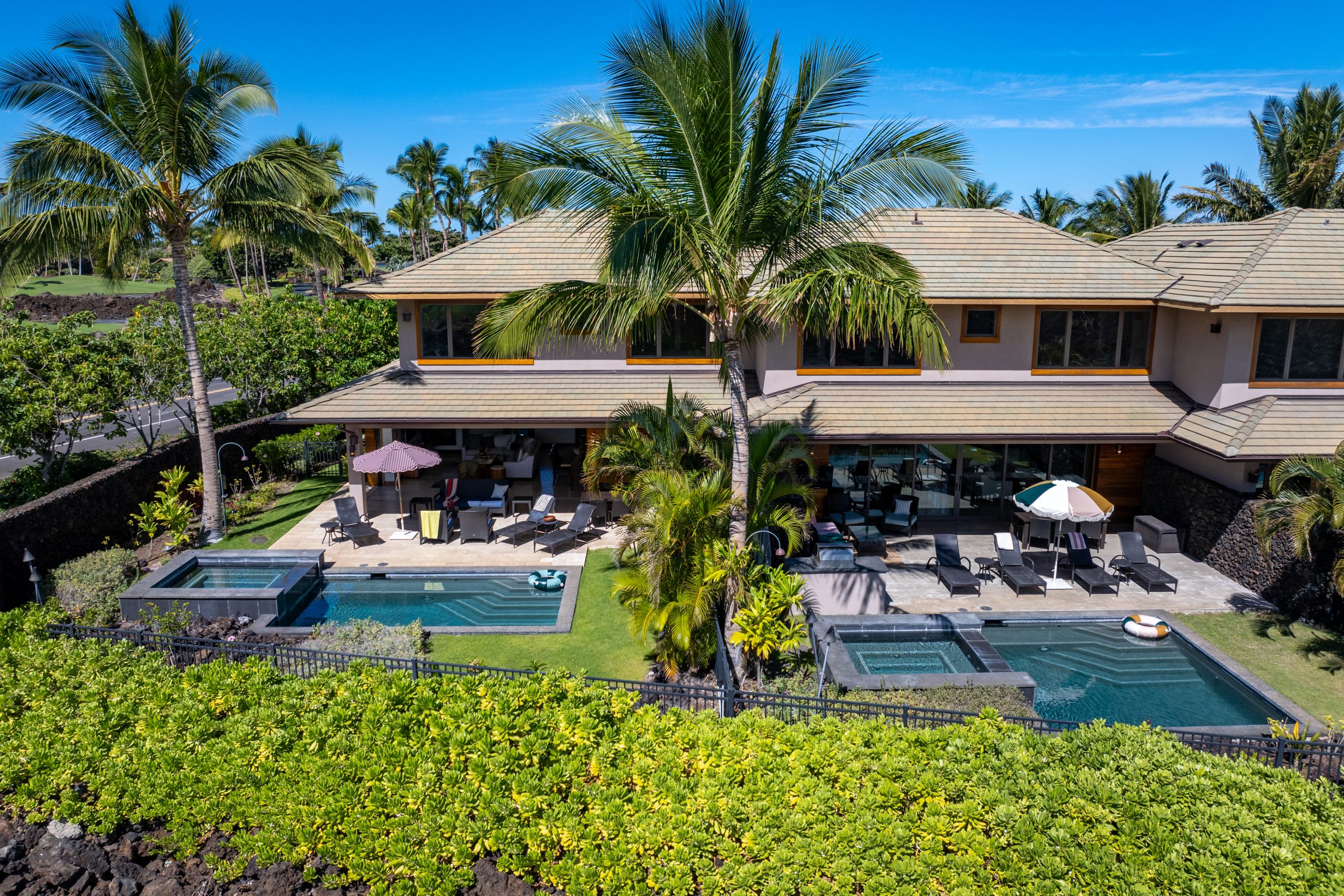 Luxury Mauna Lani villa with tropical garden, private pool, and sun loungers under palm trees.