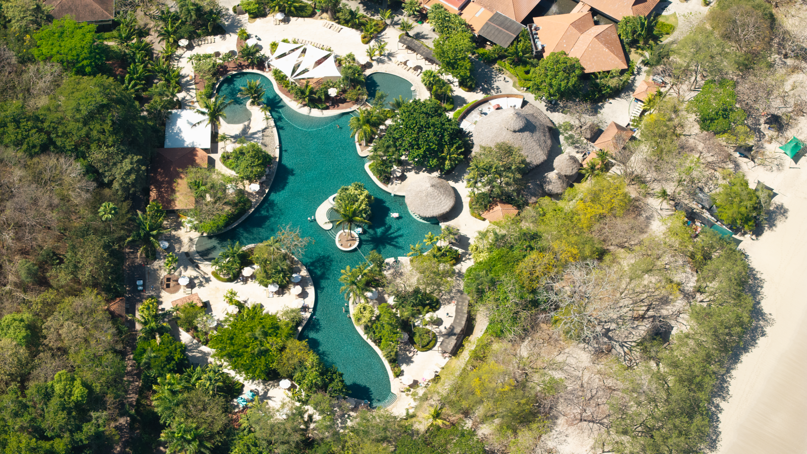 Aerial view of Reserva Conchal coastline with beaches, golf course, and lush tropical hills.