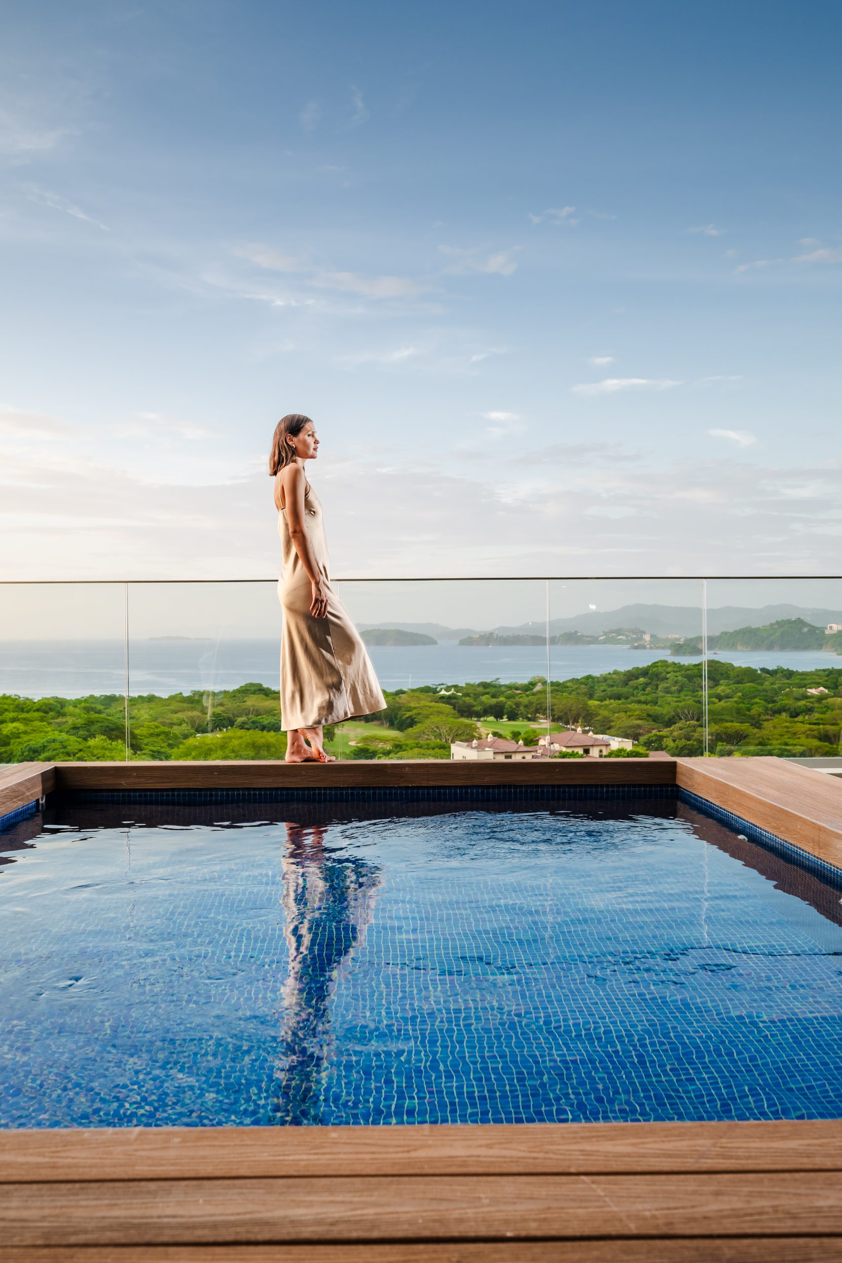 A woman standing over the infinity pool in Reserva Conchal Penthouse