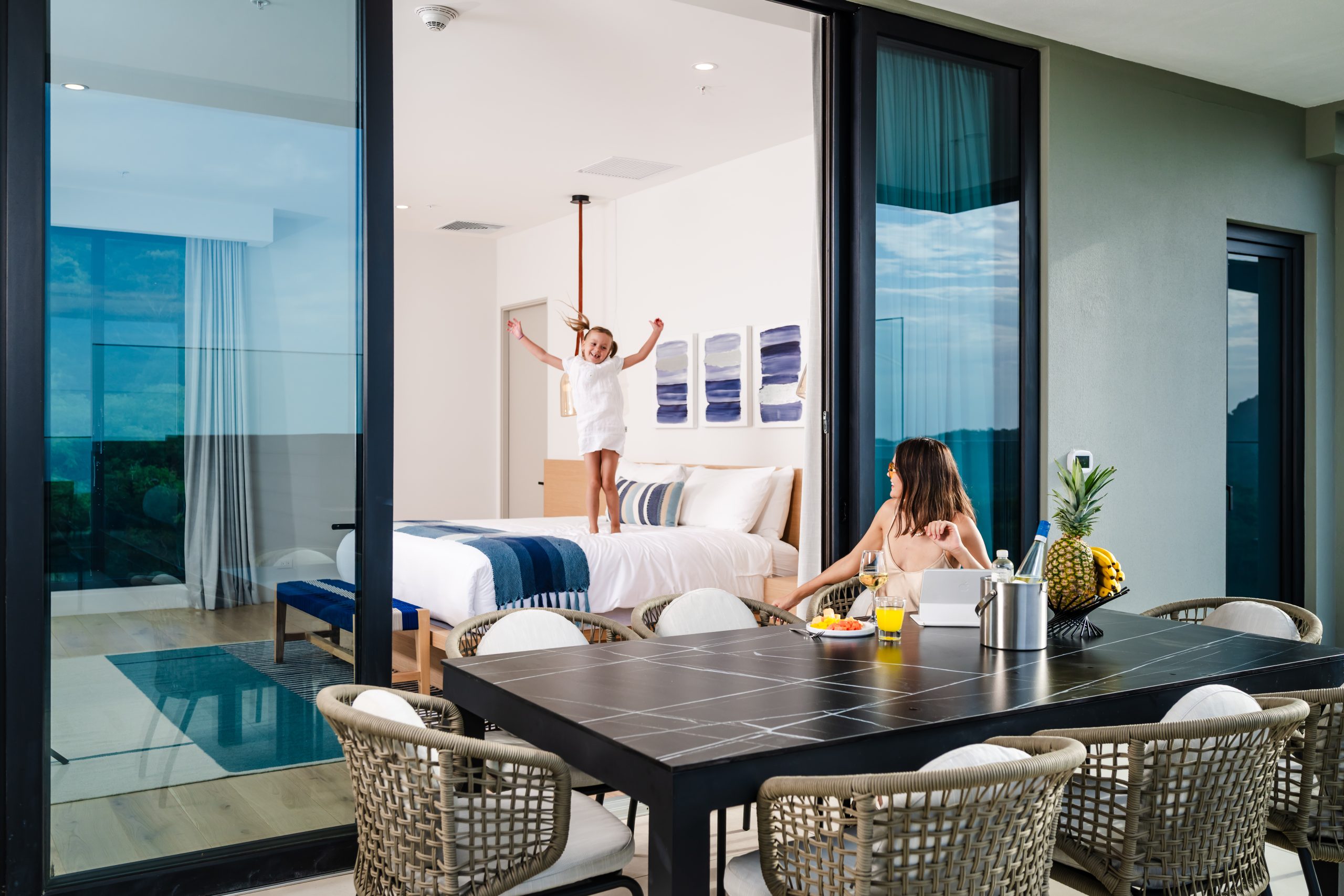 Girl Jumping on top of the Bed and a Woman Sitting on the Luxury Dining Space at the Terrace of Solaris Reserva Conchal Penthouse in Costa Rica
