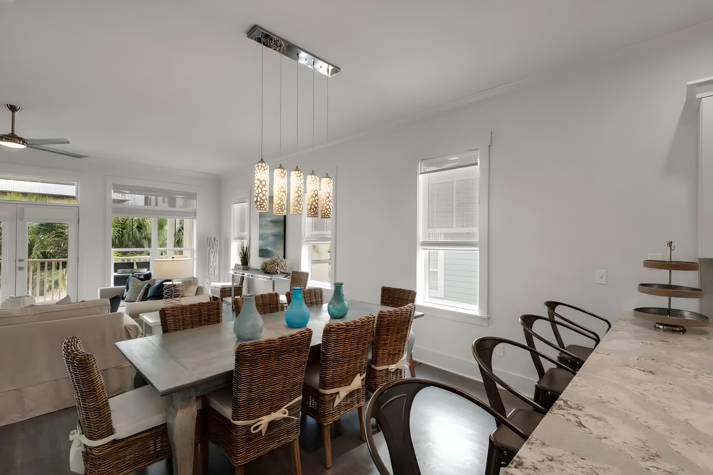 Luxury dining area in Seacrest Beach home featuring modern decor, woven chairs, and decorative lighting, ideal for family gatherings or romantic getaways near the Emerald Coast.