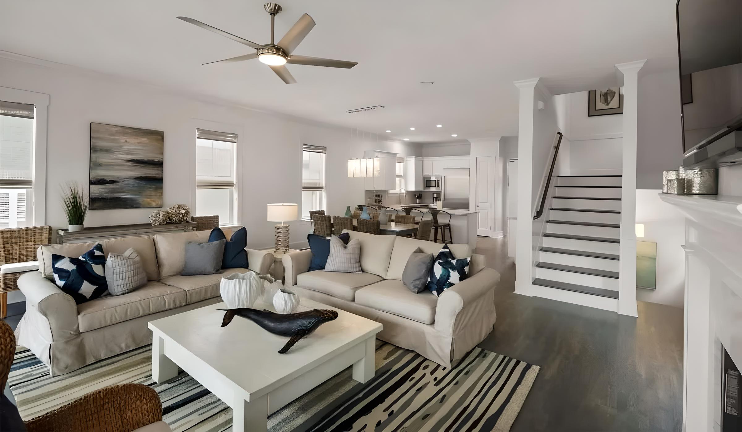 Luxury living room in Seacrest Beach home featuring modern decor, comfortable seating, and an open layout with kitchen and dining area visible.