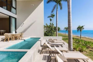 Contemporary luxury villa by Equity Residences in Nuevo Vallarta with an infinity-edge pool, open-air terrace, and lush palm trees overlooking a sunny coastal setting.