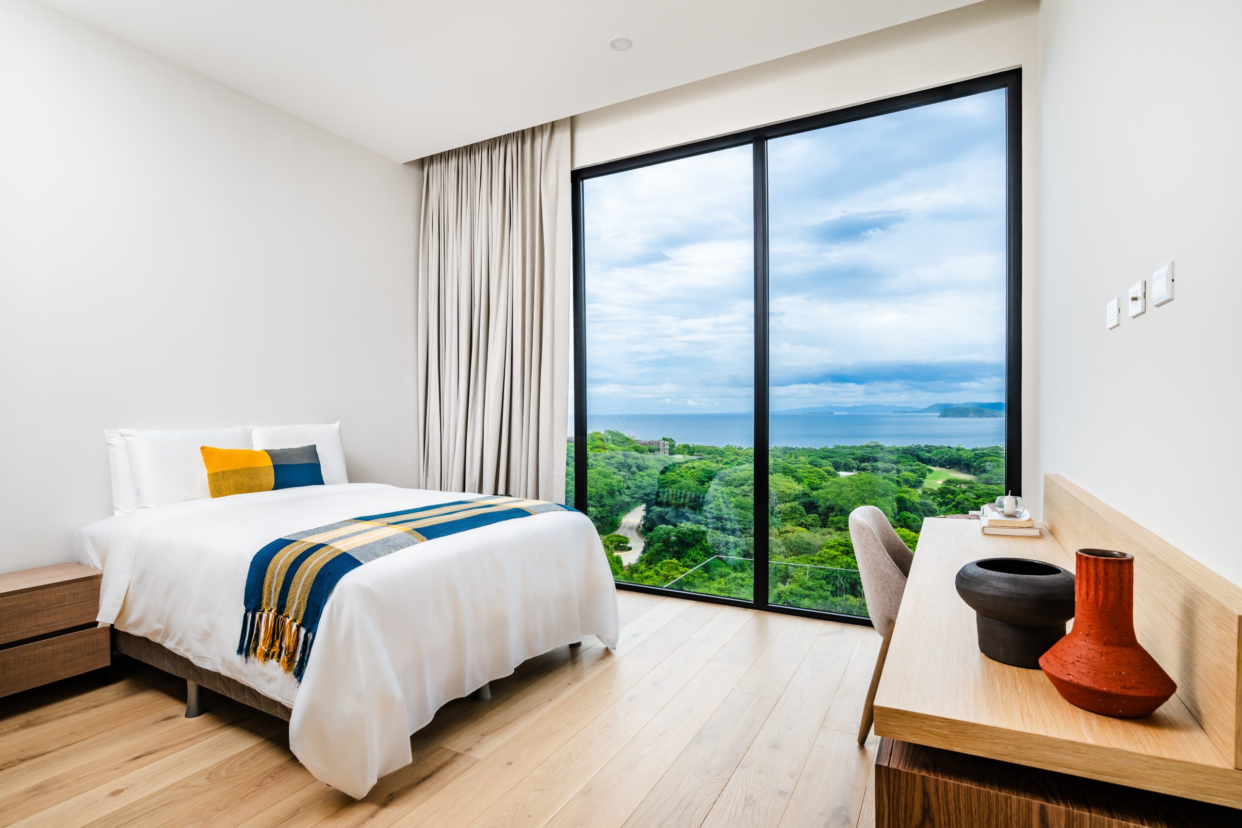 Elegant bedroom with floor-to-ceiling windows and sea views at Solaris Reserva Conchal