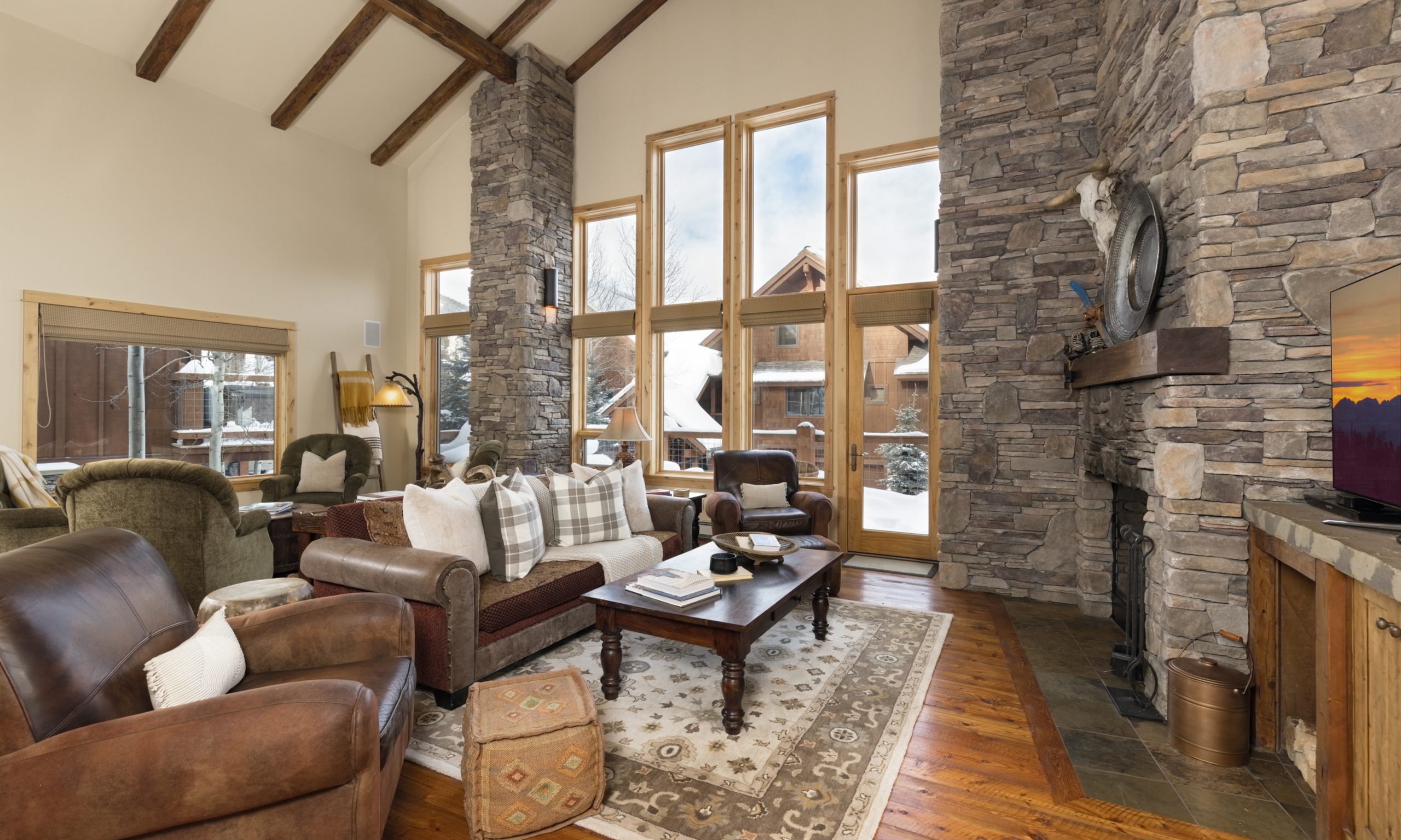 Big Sky ski-in:ski-out lodge living space with rustic wood beams, cozy seating, and mountain views