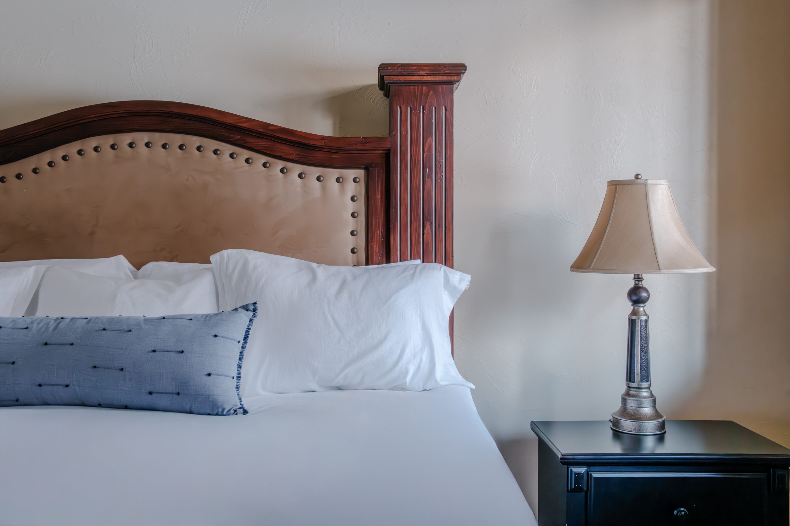Close-up of king bed in Big Sky resort bedroom with rustic wood headboard, white linens, and cozy alpine design