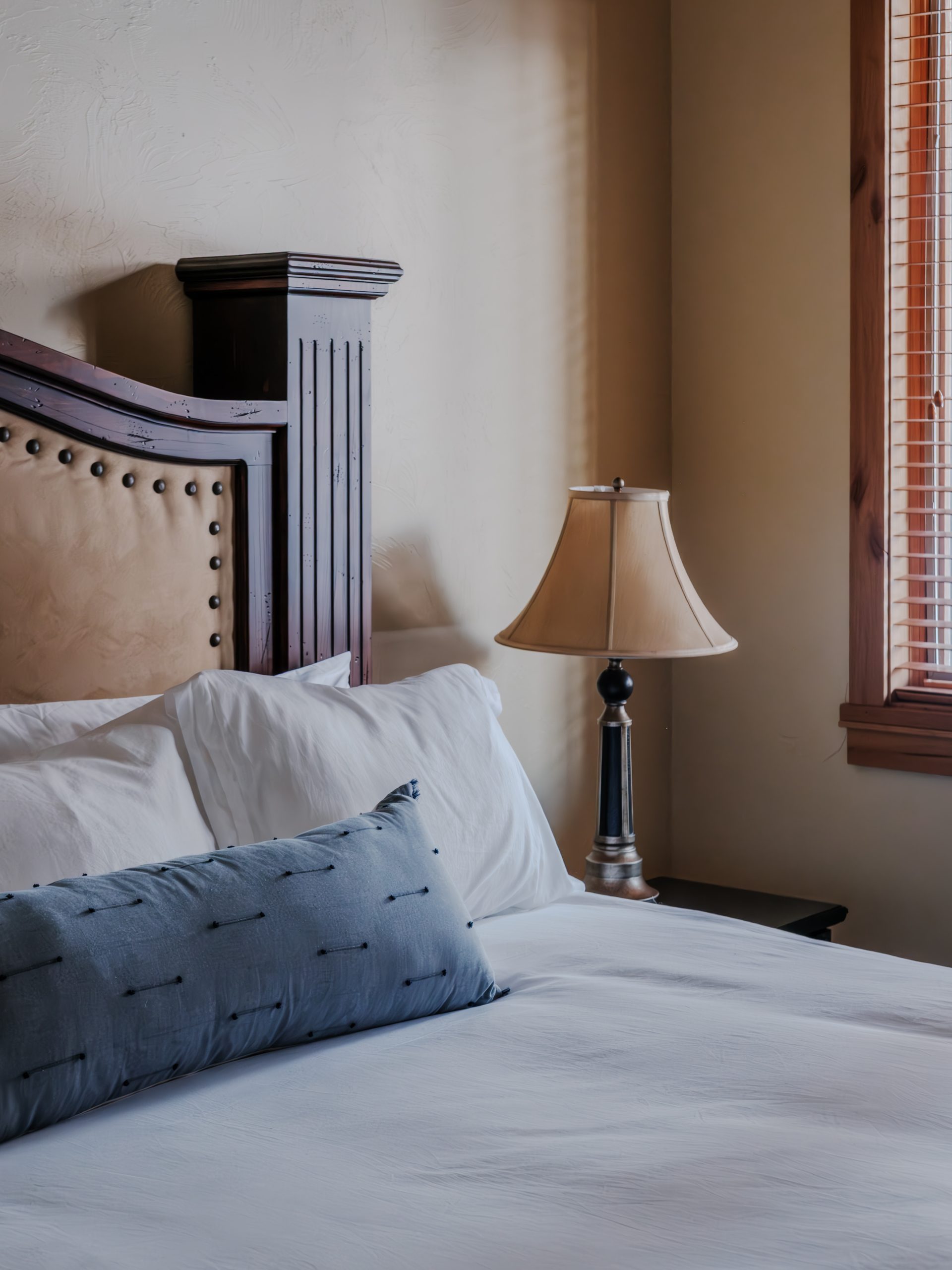Close-up of king bed in Big Sky resort bedroom with rustic wood headboard, white linens, and cozy alpine design