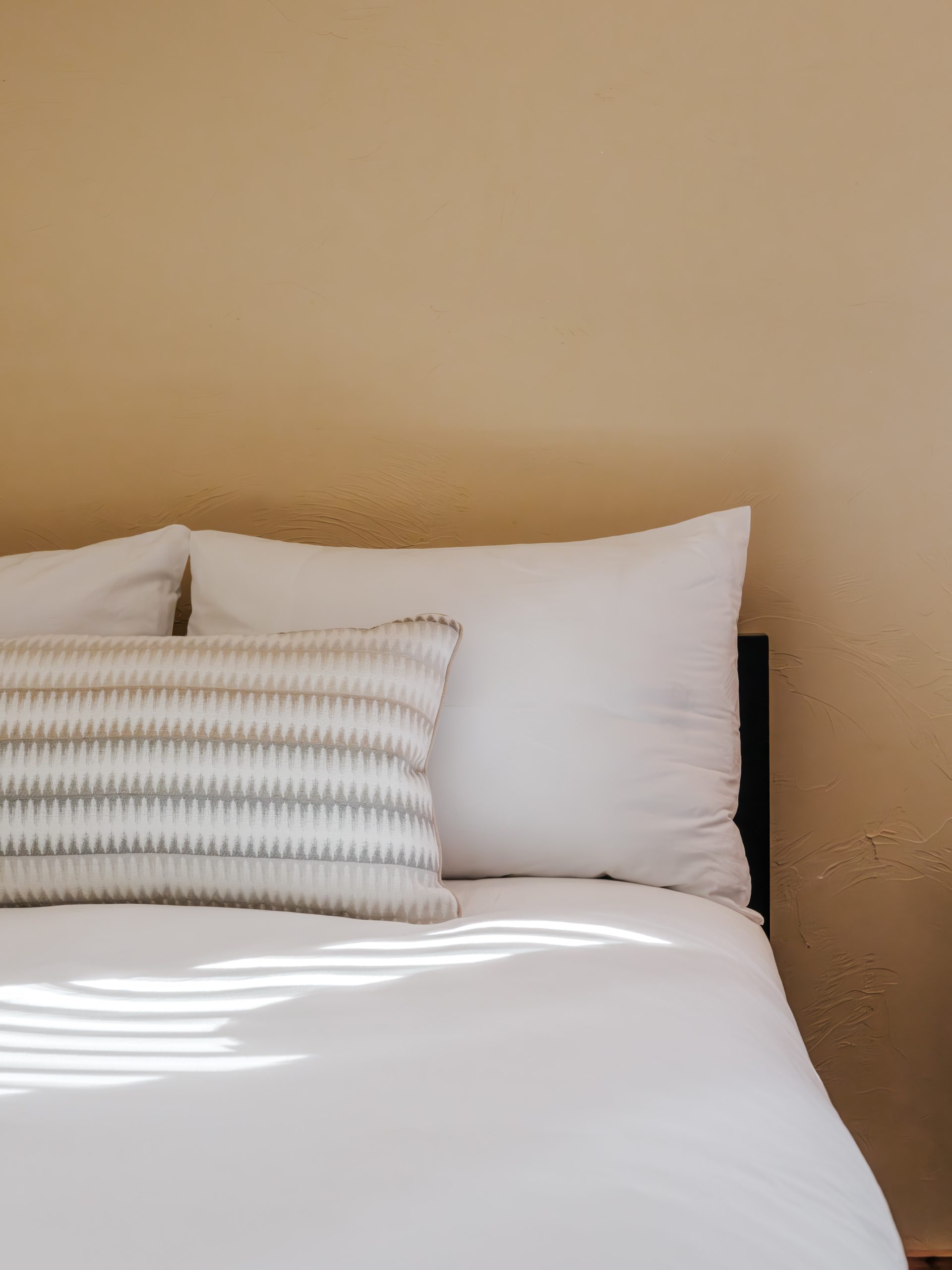 Close-up of queen bed in Big Sky resort bedroom with textured accent pillow, white linens, and natural light
