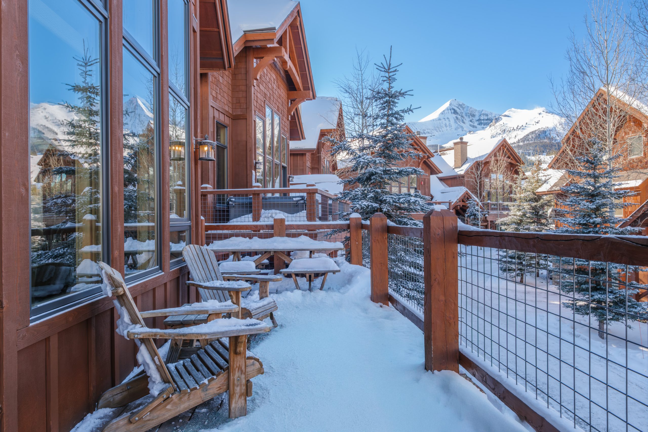 Snow-covered Big Sky resort balcony with outdoor seating and mountain views