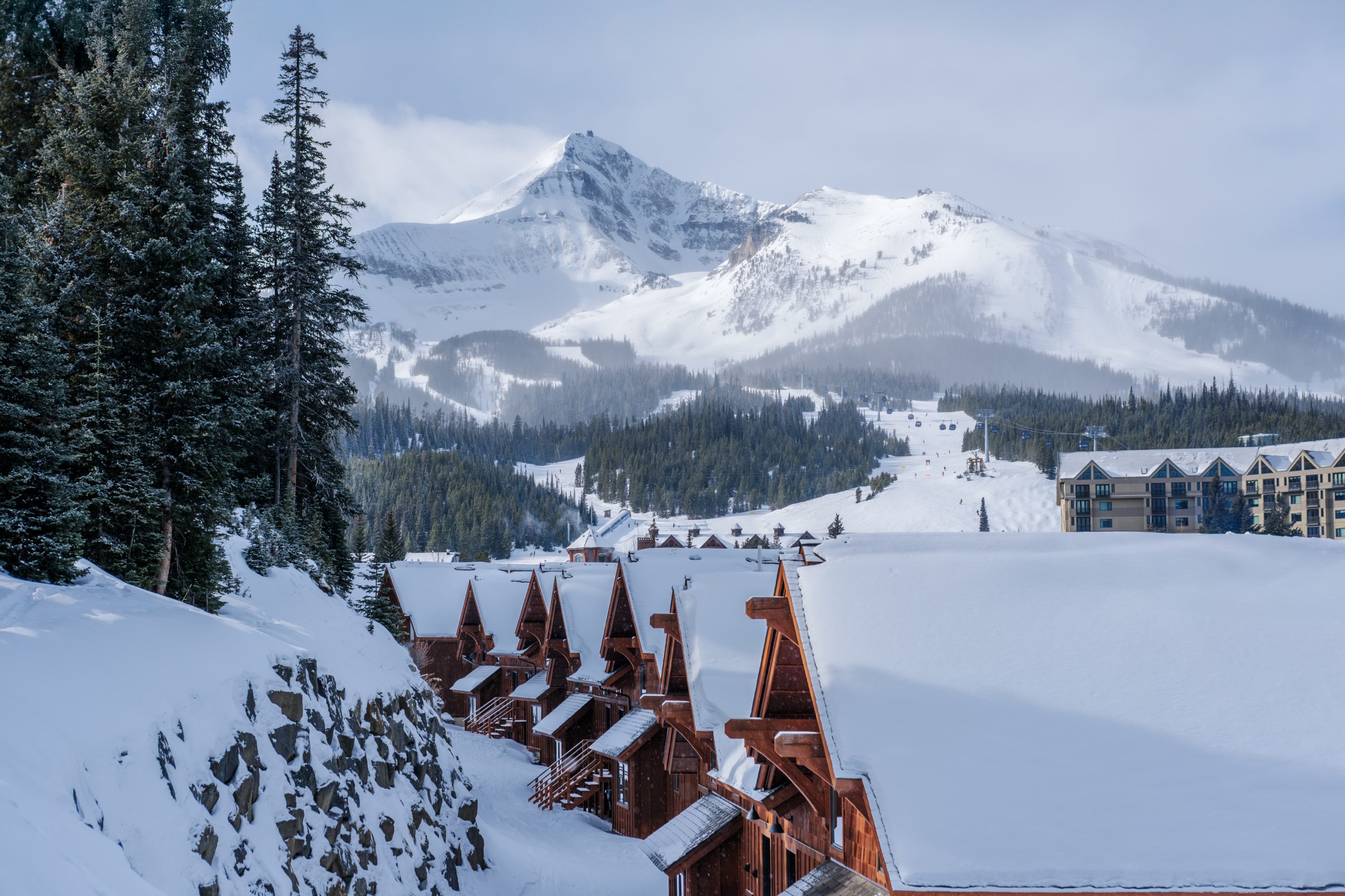 Snow-covered Big Sky ski resort lodges with alpine architecture and dramatic mountain peaks in the background