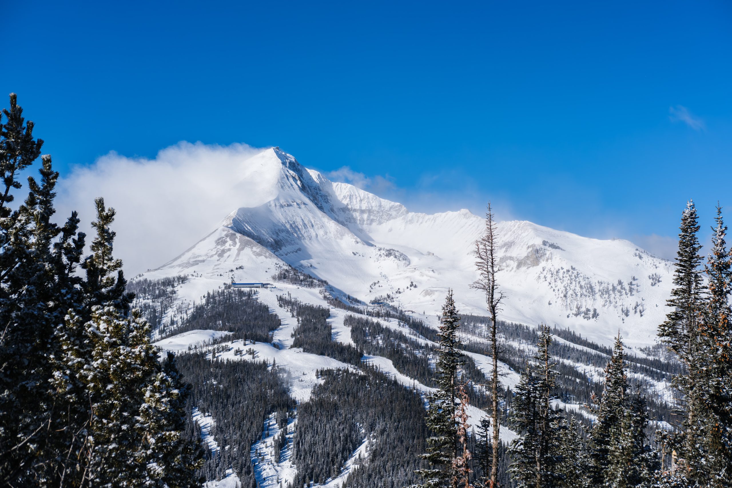 Panoramic winter view of Lone Peak at Big Sky Resort with snow-covered slopes and evergreen forest