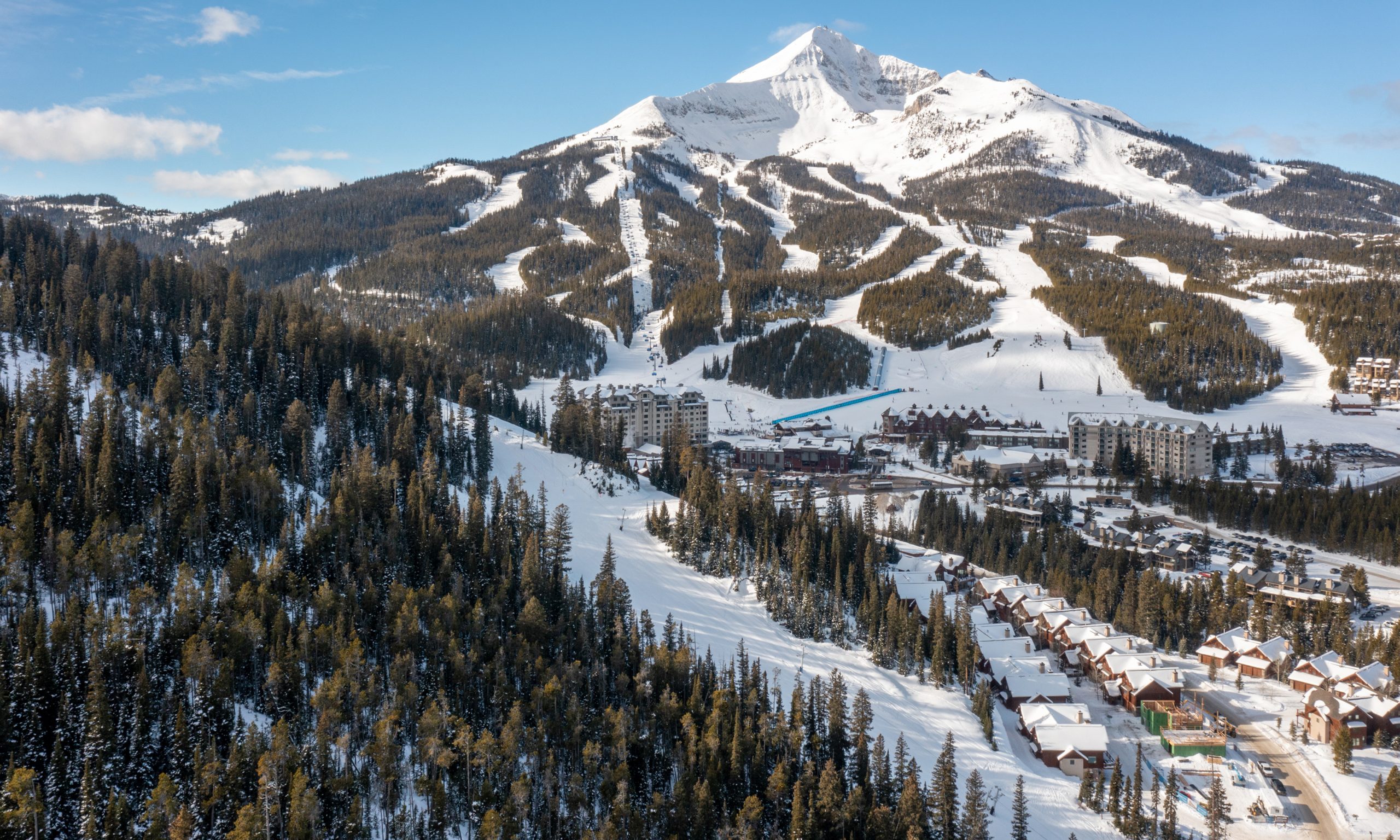 Panoramic view of Big Sky Resort showcasing the snow-dusted ski mountain rising above mountain chalets and vacation homes