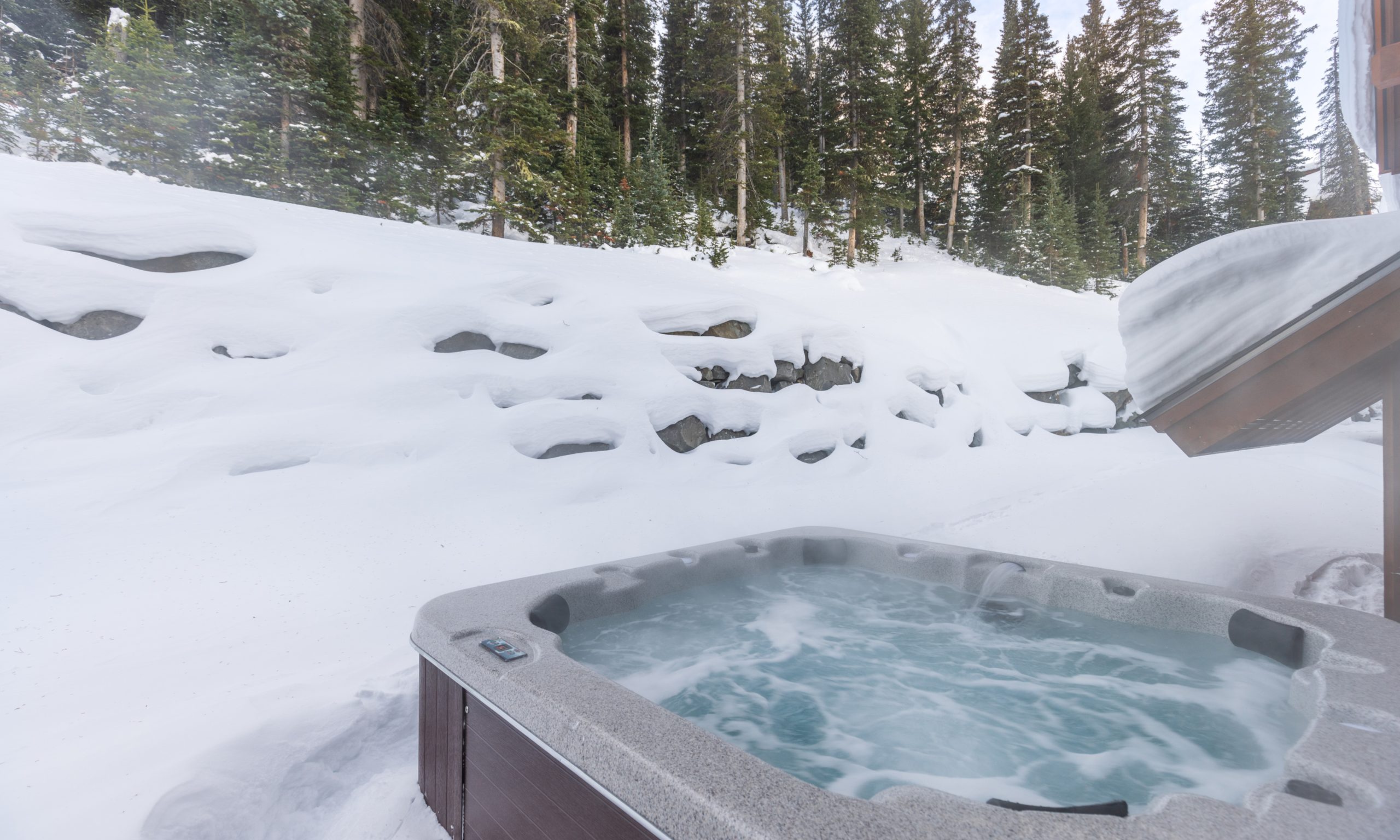 Private outdoor hot tub on the deck of a snow-covered mountain home at Big Sky Resort