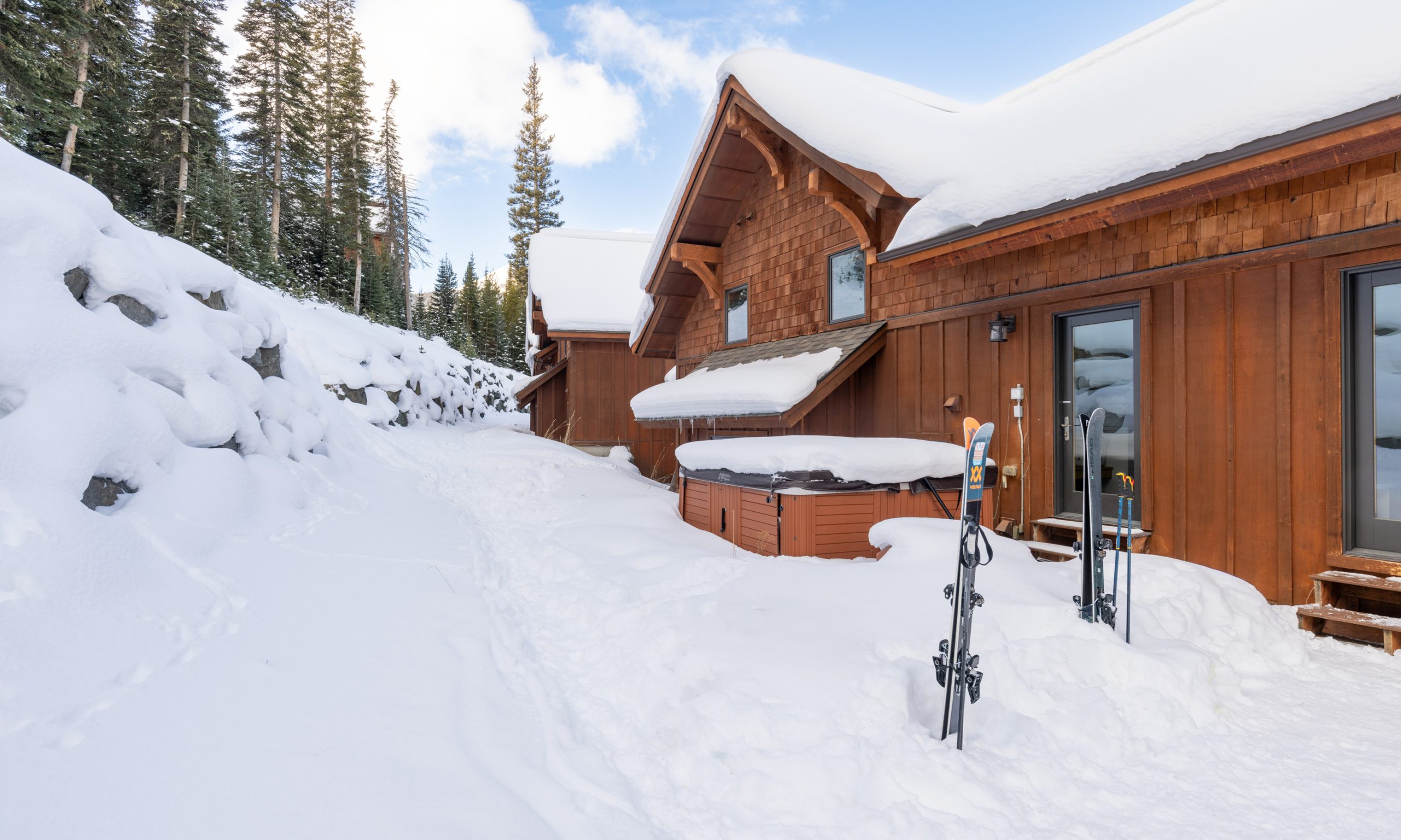 Scenic exterior view of a snow-covered mountain home with an outdoor bathtub facing Big Sky&rsquo;s slopes