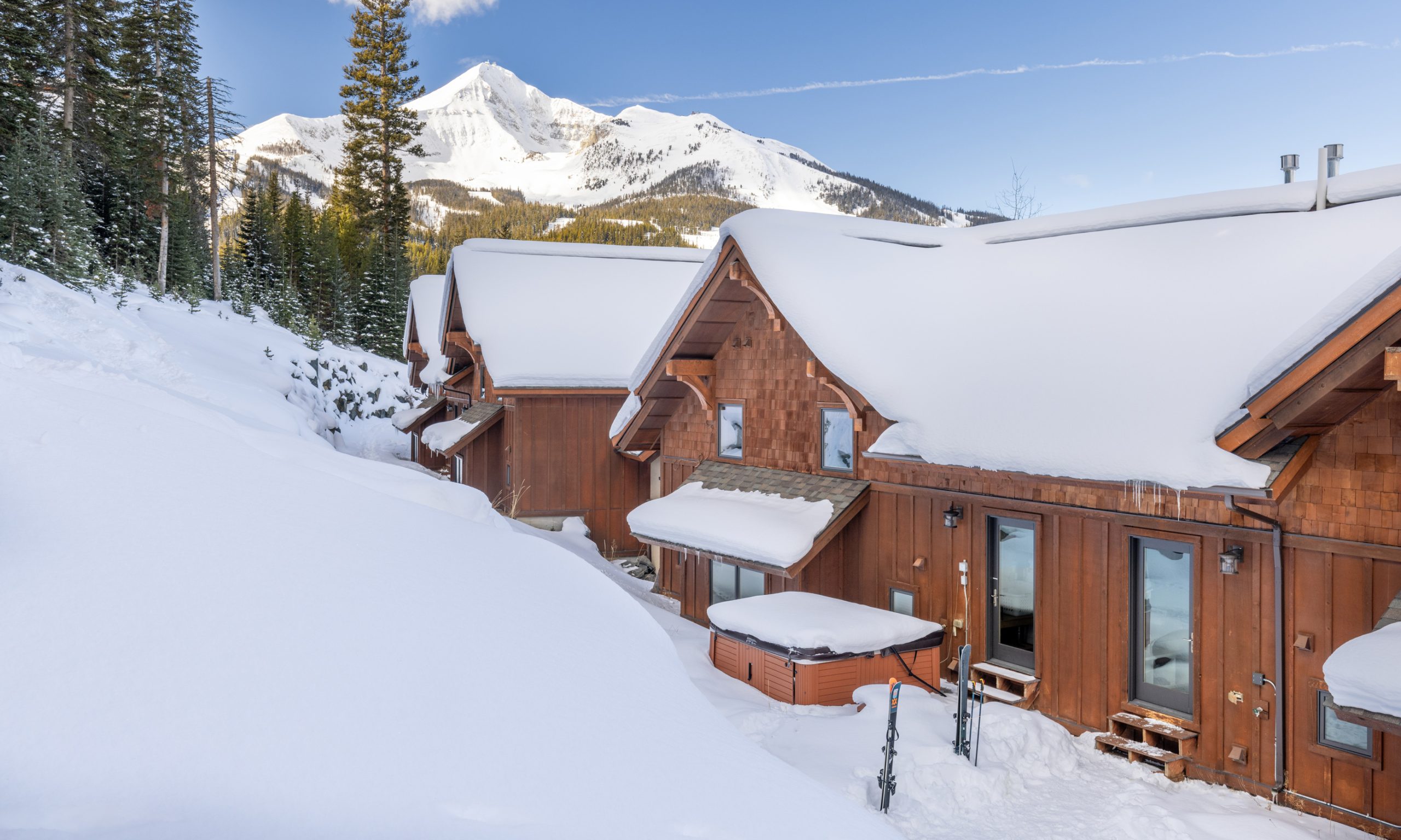 Snow-covered luxury mountain home at Big Sky Resort with outdoor hot tub and ski-in:ski-out access