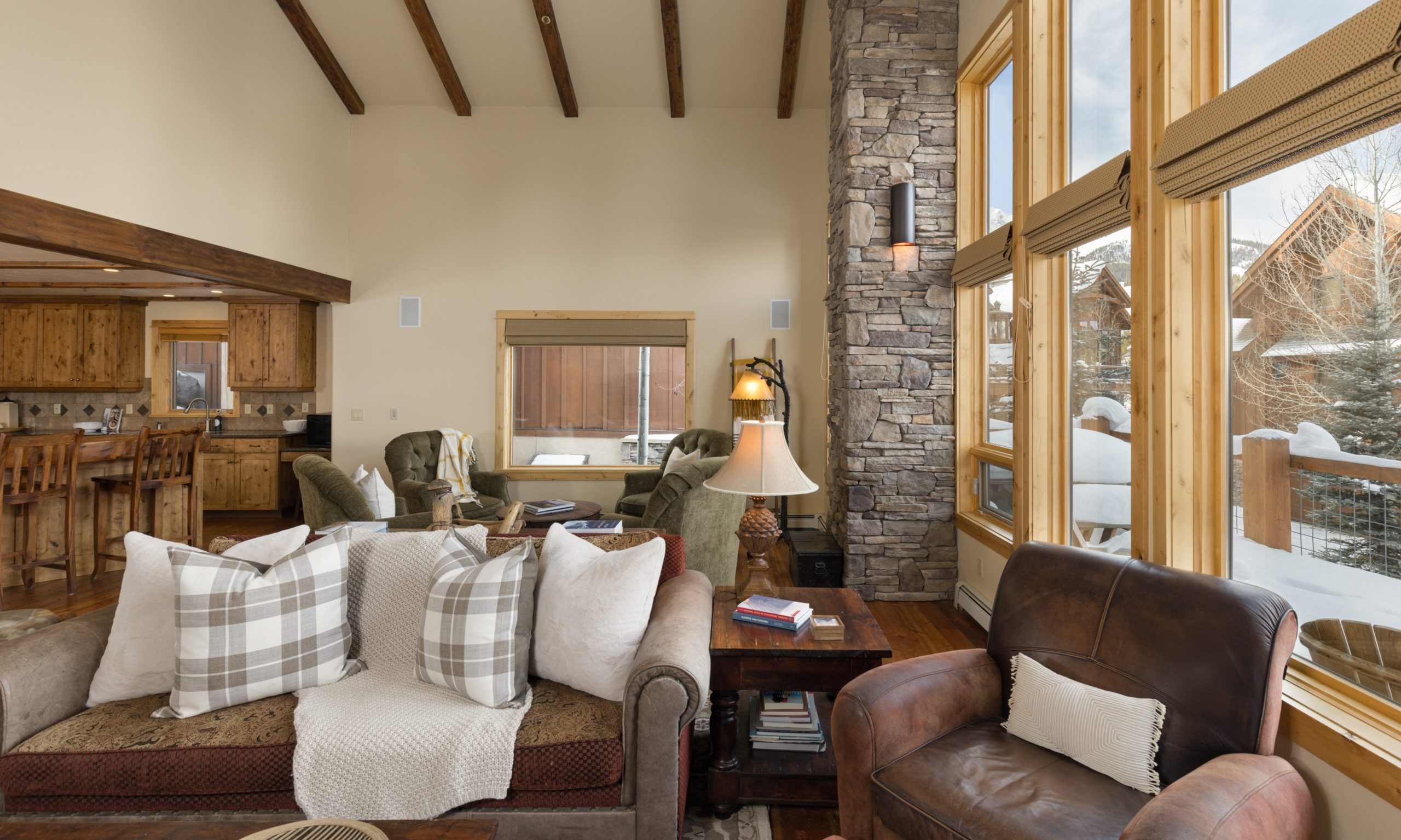 Spacious great room with vaulted ceilings, stone walls, and panoramic mountain views in a Big Sky luxury home