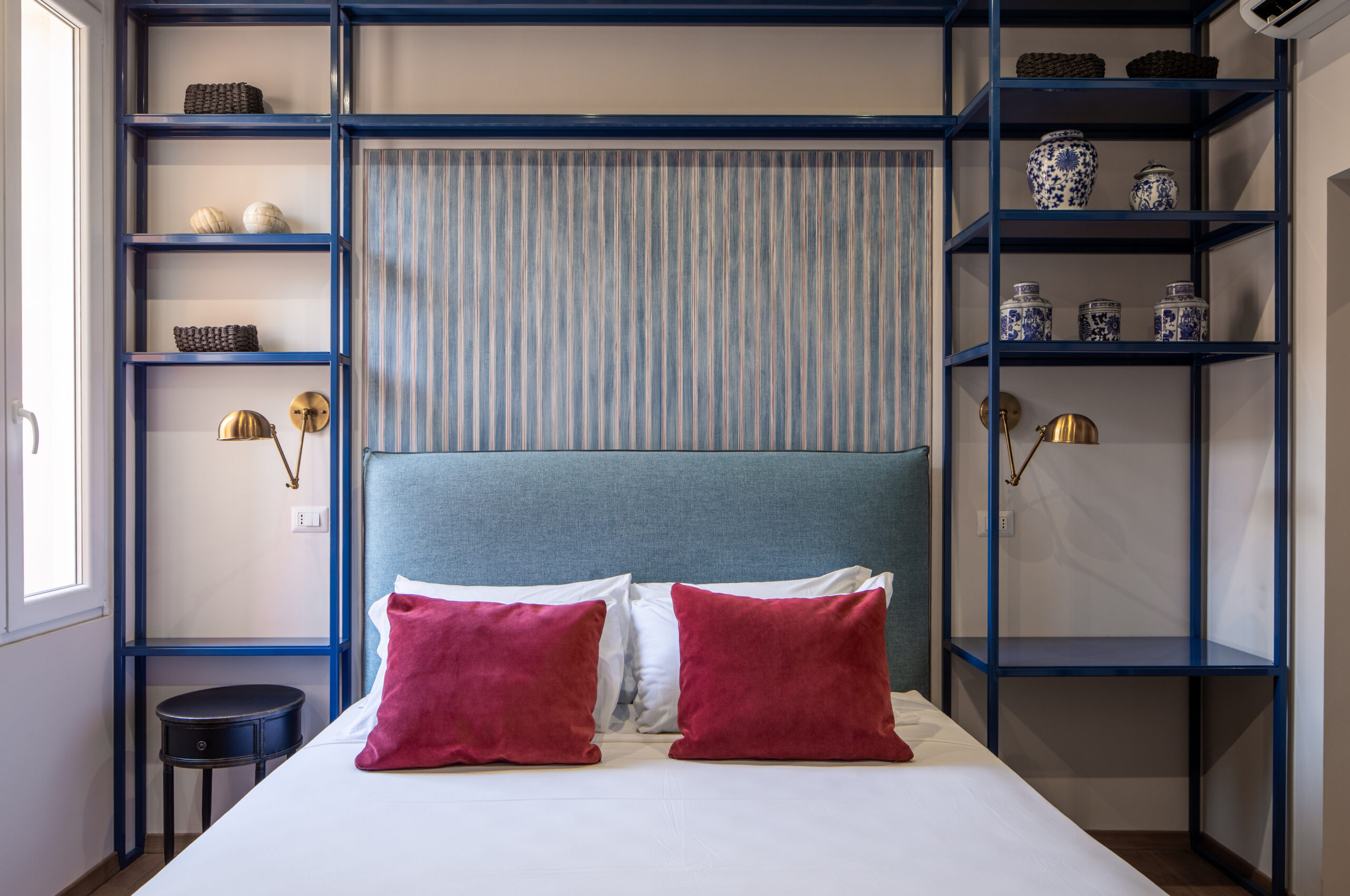 Elegant bedroom with an ornate ceiling, blue upholstered bed, and red accents in a Rome apartment by Equity Residences