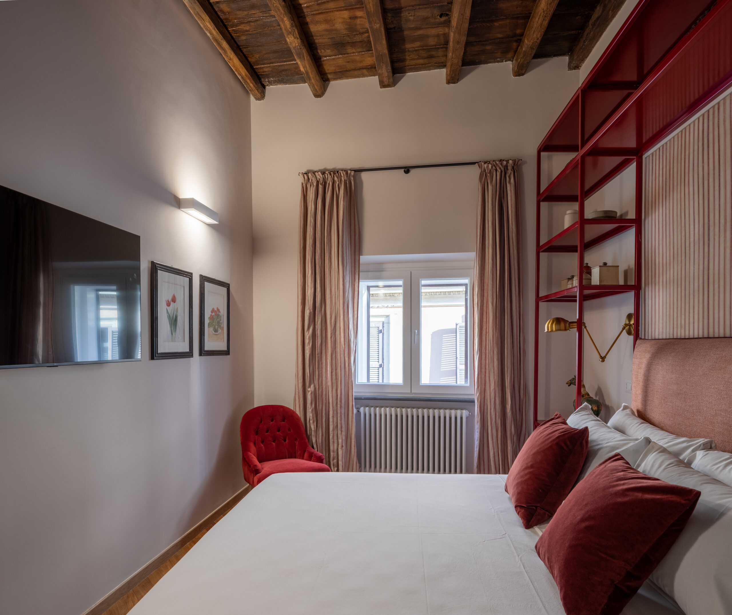 Elegant bedroom with an ornate ceiling, blue upholstered bed, and red accents in a Rome apartment by Equity Residences
