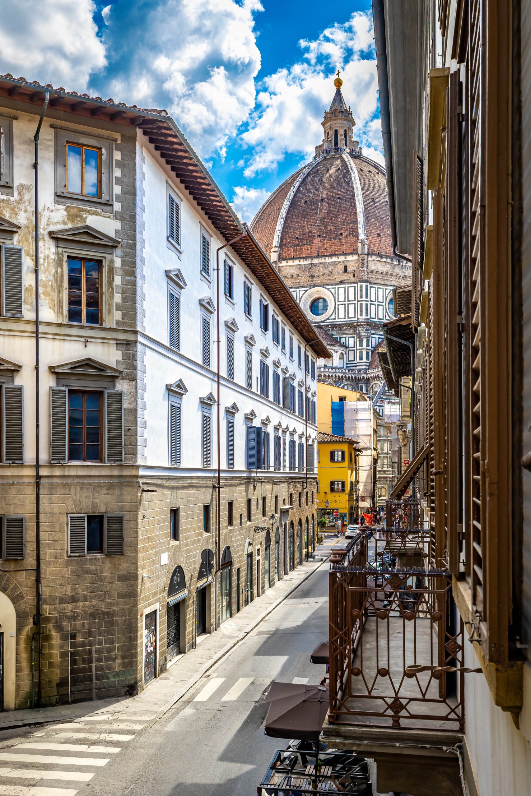 Balcony view of a narrow Florence street with the Duomo dome view.