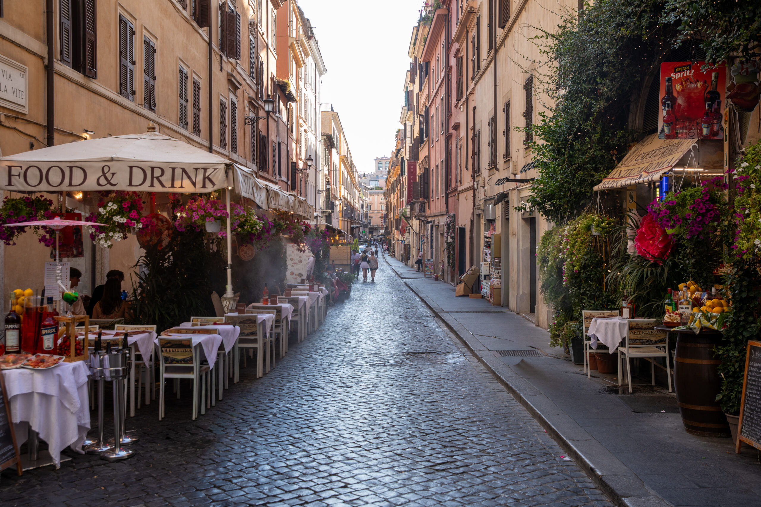 Lively pedestrian street with cafés and traditional architecture in central Rome.